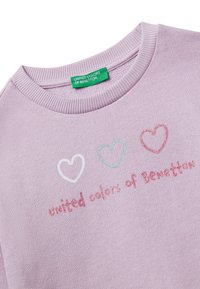 Pull lila con scollatura a girocollo rigata e la scritta "united colors of Benetton" sotto tre cuori disegnati in bianco, verde e rosso.