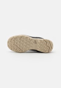 Semelle de chaussure Adidas beige avec motifs hexagonaux et texturés sur fond blanc.
