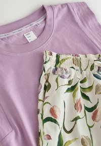 Orgonalila, kerek nyakú, rövid ujjú ing, krémszínű, elasztikus derékpántos nadrággal, zöld és rózsaszín virágmintával.