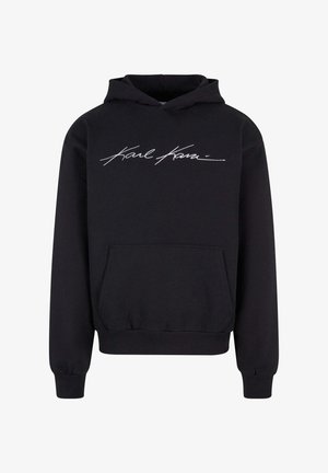 Zwarte hoodie van zacht materiaal met een voorzak en een witte geborduurde handtekening op de borst.