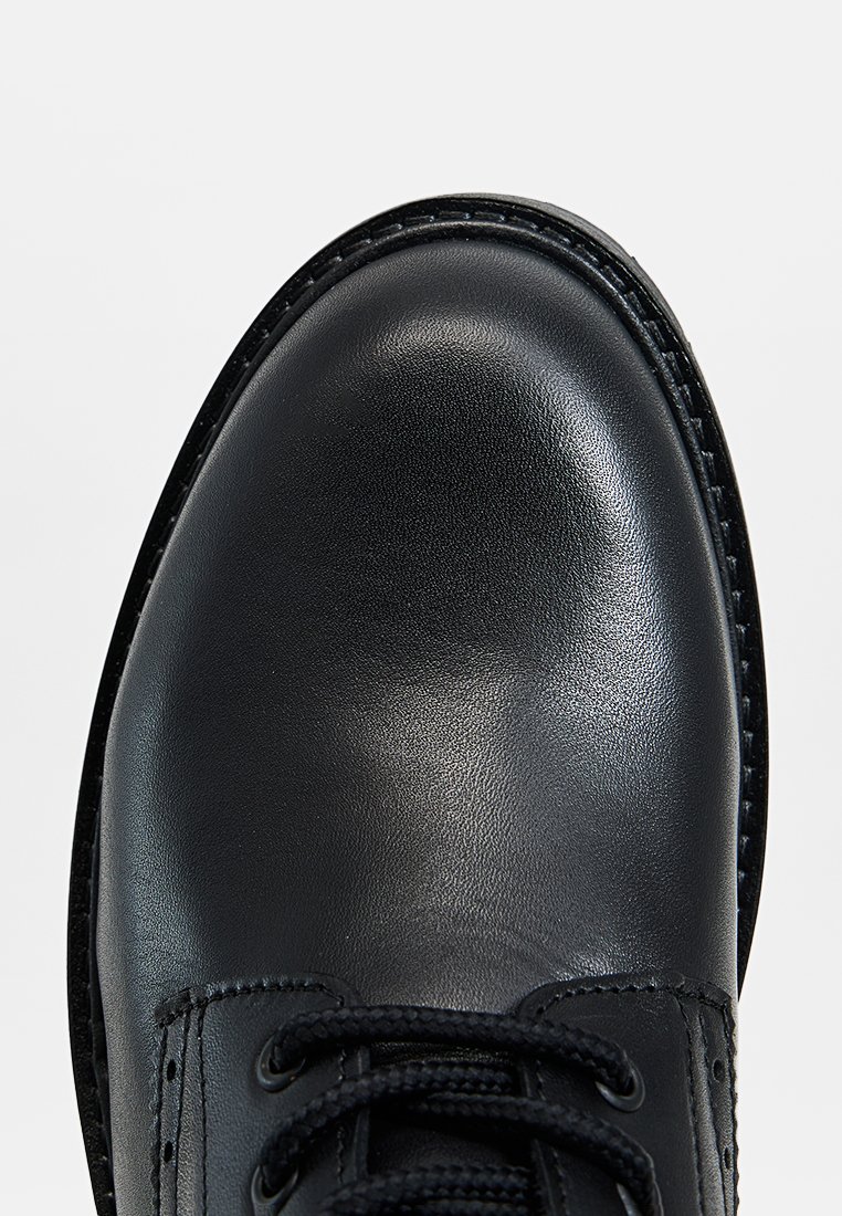 Schwarze Lederschuhe mit runder Spitze, strukturiertem Finish und genähten Details. Verfügt über schwarze Schnürsenkel und Ösen entlang des Obermaterials.