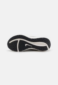 Nike-Laufschuhsohle mit einem strukturierten schwarzen Gummimuster, ausgestattet mit einer weißen Zwischensohle und einem auffälligen Logodesign.