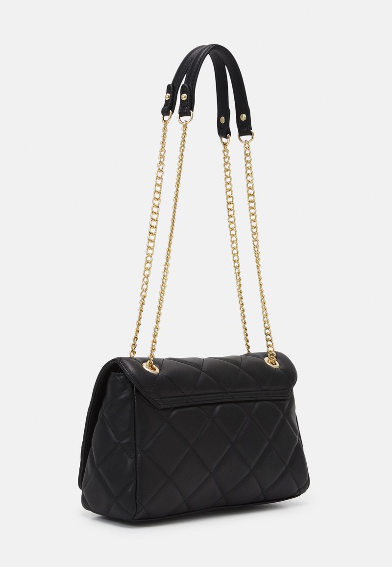 Borsa a tracolla nera trapuntata con catene dorate e dettagli in pelle. Presenta un design a fibbia e un motivo a diamante sulla superficie.