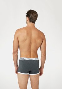 Bóxer de algodón gris con ribete blanco, que presenta una cinturilla de marca. El diseño es de un gris sólido, con un ajuste ceñido y un estilo minimalista.