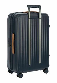 Valigia rigida blu navy con rigature verticali, manico telescopico argento, dettagli in pelle marrone e quattro ruote resistenti per la mobilità.