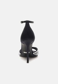 Sandal in satin nera con tacco alto e cinturino alla caviglia, impreziosita da strass sul cinturino e con un design elegante del tacco appuntito.