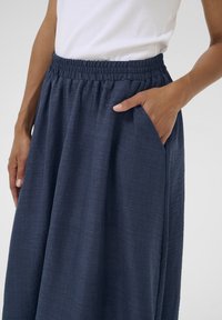 Fustă maxi bleumarin cu talie elastică și buzunare laterale, având un material texturat pentru un plus de detaliu.