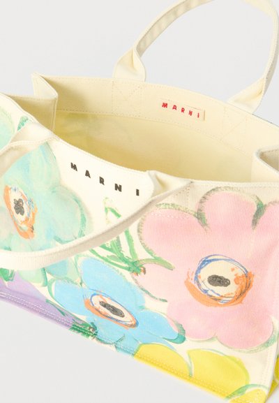 Τσάντα tote από καμβά με πολύχρωμα μεγάλα λουλούδια και το λογότυπο "Marni" κοντά στις λαβές, θέα από πάνω που δείχνει την ετικέτα στο εσωτερικό.