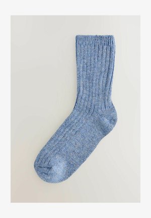 Blå ribbede sokker lavet af et tekstureret strikmateriale, med en forstærket tå og hæl, og med subtile farvepletter gennem hele.