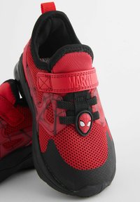 Rote und schwarze Sneakers mit einem Obermaterial aus Mesh, ausgestattet mit einem Spider-Man-Emblem, verstellbarem Riemen und Gummisohle.