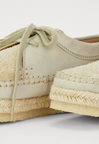Lichtbeige espadrilleschoenen met een gestructureerde jute zool, voorzien van een bovenwerk van suede, stikdetails en bijpassende veters.