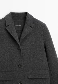 Ciemnoszary wełniany płaszcz z klapami, trzema czarnymi guzikami, dwoma kieszeniami na klapki z przodu oraz metką "Massimo Dutti" wewnątrz kołnierza.