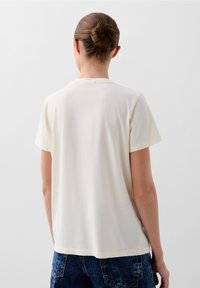 Kurzärmliges, cremefarbenes T-Shirt aus weichem Stoff, mit Rundhalsausschnitt und lockerer Passform sowie glatter Textur.