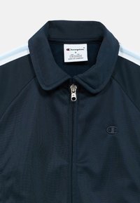 Αθλητικό μπουφάν ναυτικού μπλε χρώματος με όρθιο γιακά, πλήρης φερμουάρ και κάθετες ρίγες σε ανοιχτό μπλε χρώμα στους ώμους. Κεντημένο λογότυπο Champion.