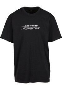 Sort bomulds T-shirt med hvid tekst: "LAS VEGAS The Gambling Capital" i en blanding af fede og kursiverede skrifttyper. Korte ærmer, rund hals.
