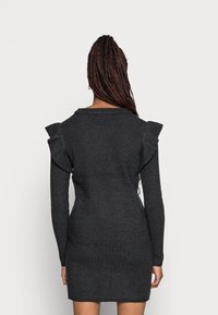 Abito a maglia grigio scuro con maniche lunghe, dettagli arricciati sulle spalle e silhouette aderente. Tessuto strutturato con motivo a coste.