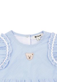 Garment a righe azzurro chiaro con colletto rotondo, maniche a volant e una toppa di un orsetto ricamata sul petto. Materiale lavabile in lavatrice.
