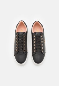 Sneaker in pelle nera con una finitura liscia, occhielli in oro rosa, lacci rotondi e suola bianca con una punta texturizzata.