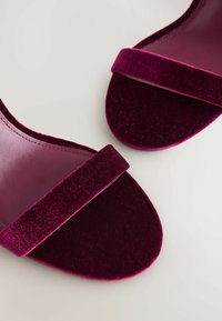 Velours open-toe sandalen in diep bordeaux met brede banden. Heeft een gladde binnenvoering en een gestructureerde buitenzool. Eenvoudig en elegant ontwerp.
