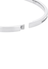 Bracciale in metallo argentato con un design elegante e minimalista, caratterizzato da un accento testurizzato e un dettaglio di chiusura circolare.