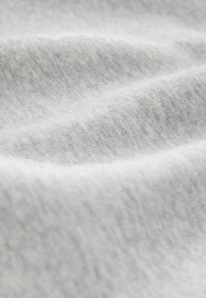 Světlá šedá tkanina s jemnou, hladkou texturou; vykazuje jemné variace v odstínech typické pro bavlněné nebo jersey materiály.
