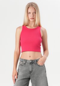 Rosa ribbet crop-top med rund hals, parret med grå højtaljede jeans med knap og lommer. Glat tekstur.
