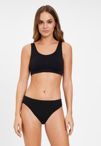 Bralette nera senza cuciture con spalline larghe, scollatura arrotondata e dettaglio di arricciature sottili sul davanti, abbinato a slip neri coordinati.