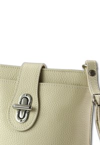 Sac à main en cuir couleur crème avec finition texturée, doté d'une fermeture métallique et d'une sangle ajustable, conçu avec des lignes épurées et des accents de couture.