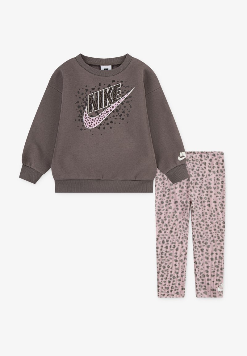 Pilkas džemperis su juodu ir rožiniu Nike logotipu; derinamas su rožinėmis leginsais, turinčiais subtilų leopardą primenantį raštą. Minkšta, raukšlėta medžiaga.
