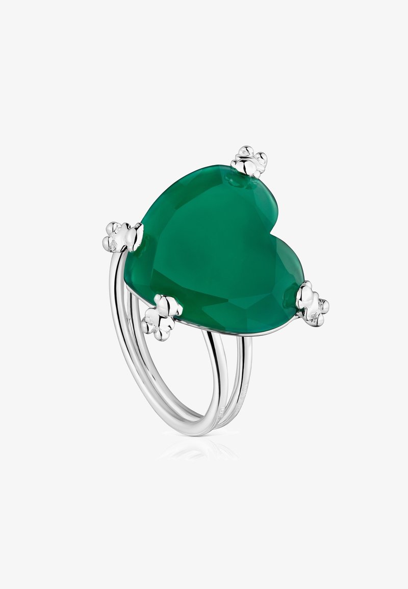 Anello con pietra verde a forma di cuore, montato in argento lucido. Presenta accenti floreali e un design della fascia elegante e aperta.