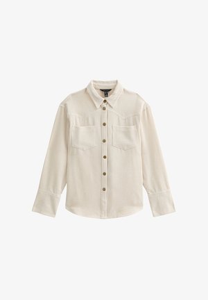 Beige langærmet skjorte i kordfløjl med knapper foran, to brystlommer, spidst krave og brede manchetter.