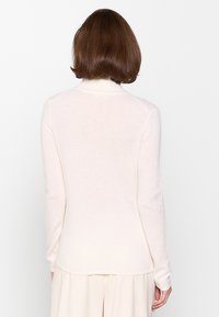 Helles rosa, langärmliges Sweatshirt mit einem hohen Kragen. Hergestellt aus weichem Material, mit einer glatten Textur und einem enganliegenden Design.