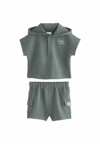 Graues Zweiteiler-Outfit mit einem Kurzarm-Polohemd, das über eine Kapuze und Knöpfe verfügt, kombiniert mit Shorts mit elastischem Bund und seitlichen Taschen.