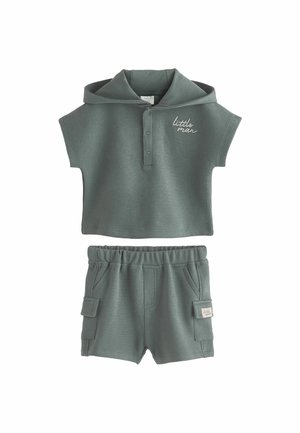 Completo grigio a due pezzi con una polo a maniche corte dotata di cappuccio e bottoni, abbinato a pantaloni corti con vita elastica e tasche laterali.