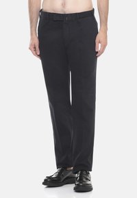 Pantaloni blu navy realizzati in tessuto leggero, con taglio dritto, tasche frontali e chiusura con zip e bottone, indossati con scarpe nere.