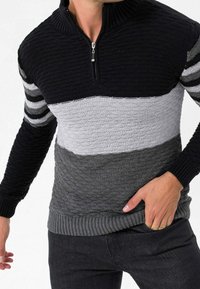 Knitted pullover with a half-zip, featuring horizontal stripes in black, grey, and light grey. Textured fabric with ribbed cuffs and hem.