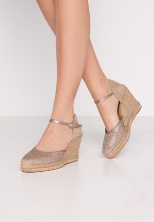 Sandalias de cuña con parte superior de purpurina dorada metálica, punta abierta y correa en el tobillo; tacón envuelto en yute para añadir textura y estabilidad.