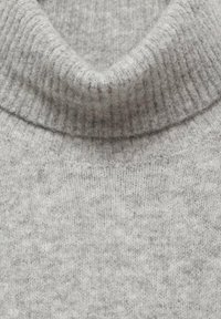 Pull en tricot gris clair avec un col roulé côtelé, texture douce avec un motif discret, et une coupe générale décontractée.
