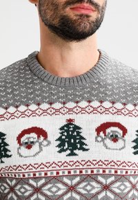 Grauer Strickpullover mit festlichem Muster, das rote und grüne Santa-Gesichter und Weihnachtsbäume zeigt, Rundhalsausschnitt, strukturierter Stoff und geometrische Akzente.