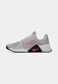 Pelēki un rozā ventilējami sporta apavi ar melnu un baltu zoli, auklām un Reebok logo uz sāna un papēža, attēloti sānu profilā.
