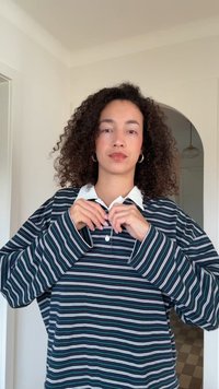 Koszulka polo z długim rękawem w paski, z białym kołnierzem, granatowym tłem oraz kontrastującymi zielonymi i białymi paskami. Miękki materiał i luźny krój.