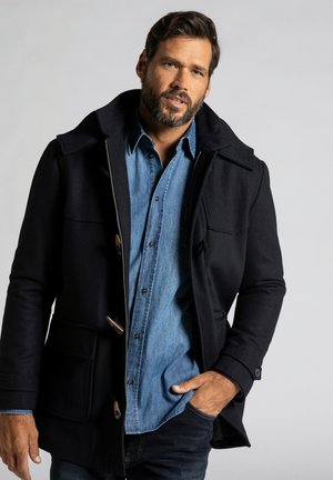 Navy wool blend coat with dual pockets, large collar, and toggle closures. Worn over a light blue denim shirt. Minimalist design.