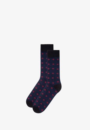 Marineblaue Socken mit dunkelroten Punkten, schwarzen Bündchen, Fersen und Spitzen, flach nebeneinander auf weißem Hintergrund ausgelegt.