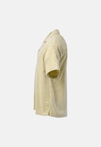 Polo en maille texturée jaune clair à manches courtes, présenté de profil sur fond blanc.