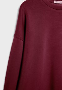 Bordeaux sweatshirt met een ronde hals en lange mouwen. Gemaakt van zachte stof met een gladde textuur. Bevat minimale stikseldetails.