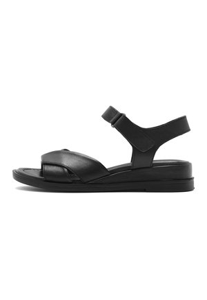 Black leather flat sandal with adjustable ankle strap and crisscross front straps on a low sole.