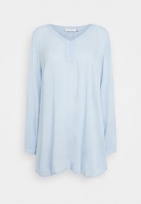 Hellblaues, langärmliges Hemd aus weichem Stoff. Verfügt über einen V-Ausschnitt mit einer kleinen Knopfleiste und einem abgerundeten Saum. Glatte Textur.