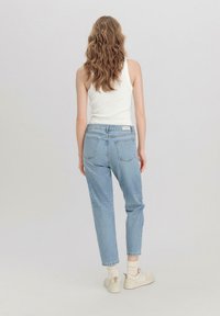 Lichtblauwe high-waisted spijkerbroek in een ontspannen pasvorm, gemaakt van denim, met vijf zakken, rafelige zomen en een label op de achterste tailleband.