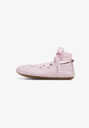 Měkká růžová kožená balerína s páskem na zavazování kolem kotníku a hnědou pryžovou podrážkou, zobrazena z boku na bílém pozadí.