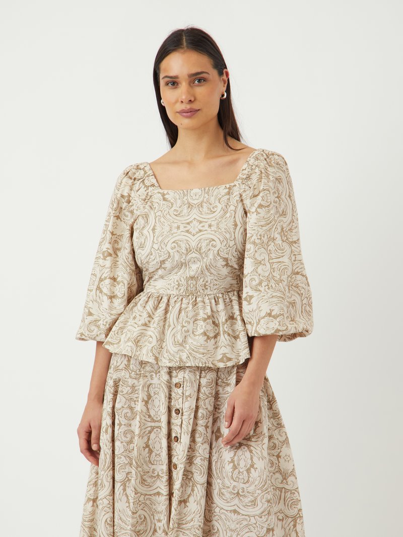 Peplum-Bluse und Rock aus cremefarbener Stoff mit aufwendigen beigen Blumenmustern. Verfügt über Puffärmel und Knopfdetails am Rock.